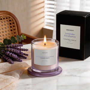 Lavender Eucalyptus candle lit on a marble table with fresh lavender sprigs and its packaging box
